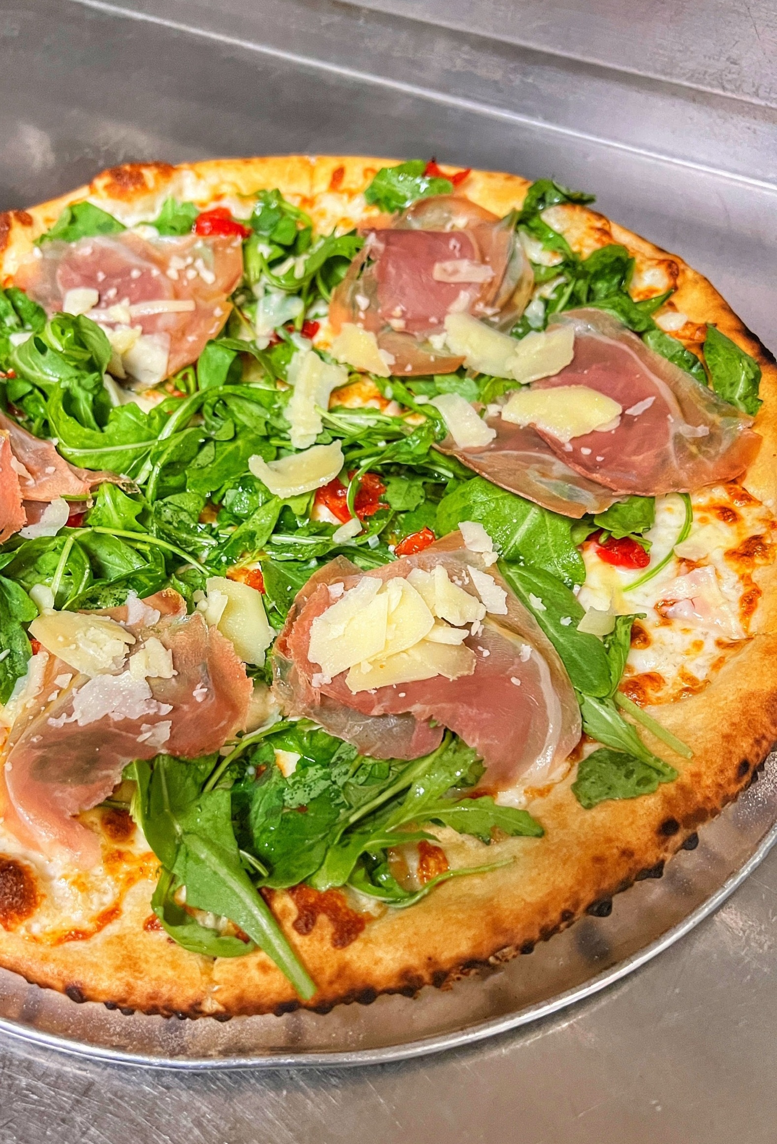 Wood-fired pizza with shaved prosciutto and parmesan
