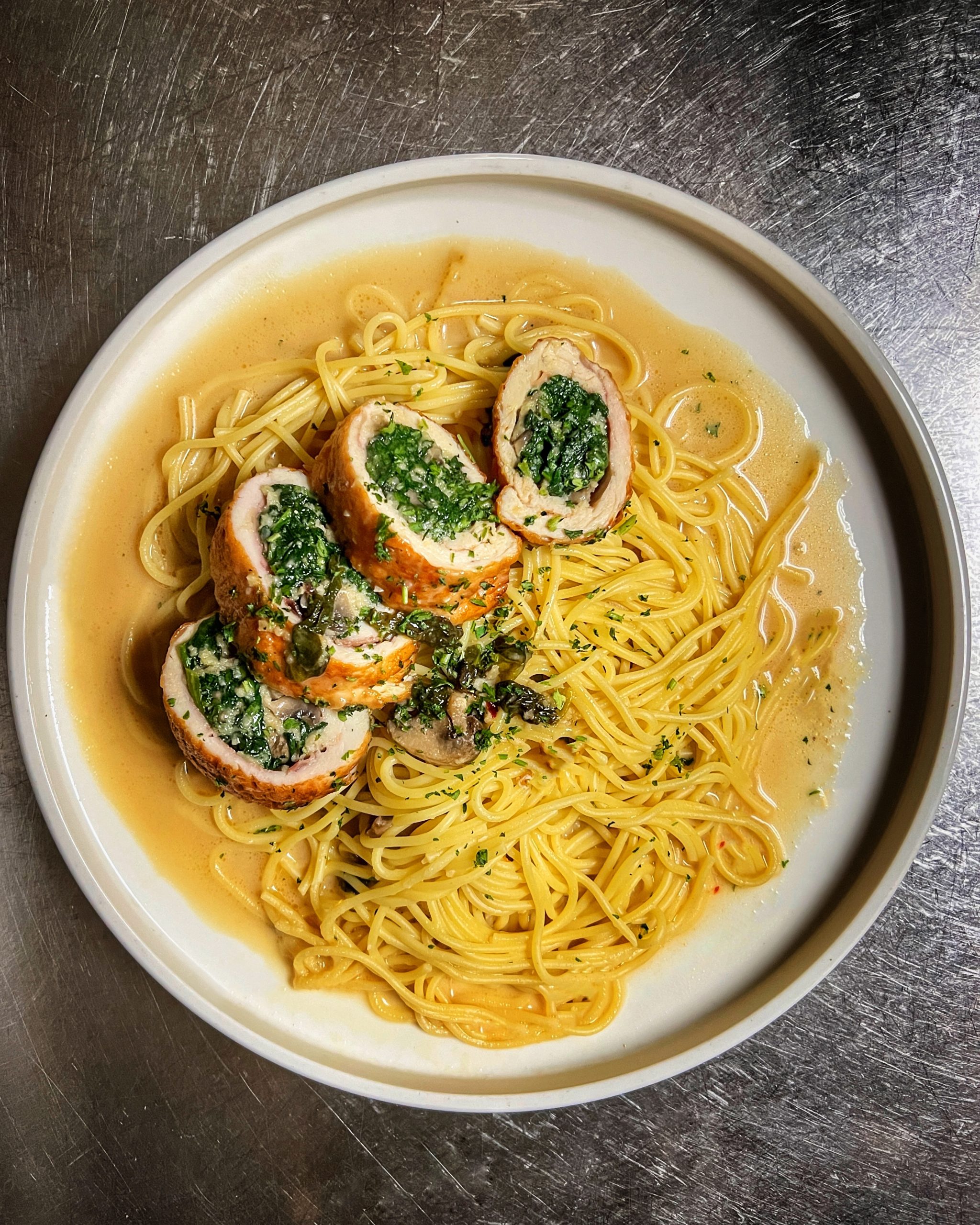 Spaghetti with stuffed chicken on round dinner plate