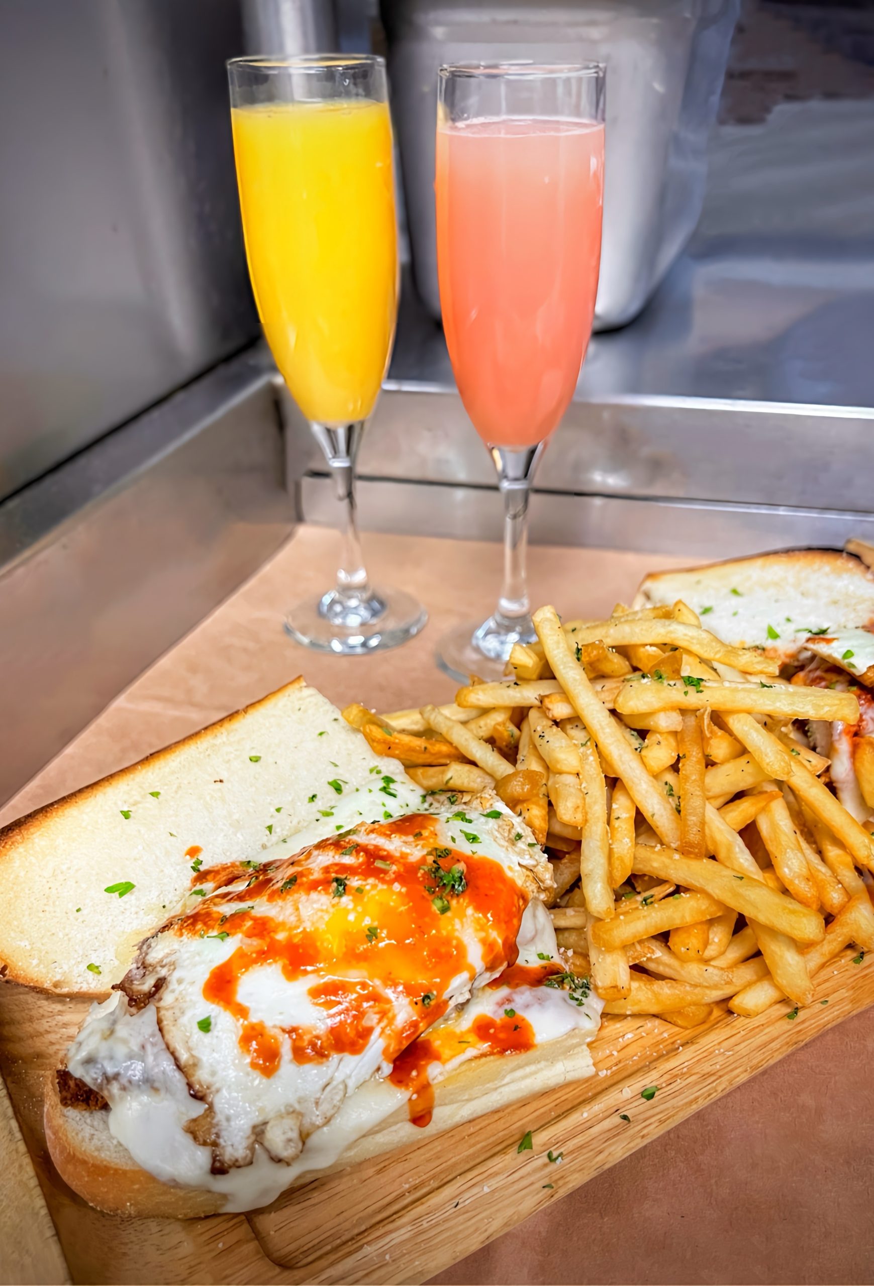 Open faced sandwich with fries and two mimosas
